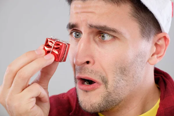 Primer plano retrato infeliz, hombre molesto sosteniendo pequeño regalo rojo — Foto de Stock