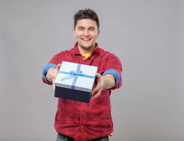 Sorrindo jovem feliz apresentando um presente — Fotografia de Stock