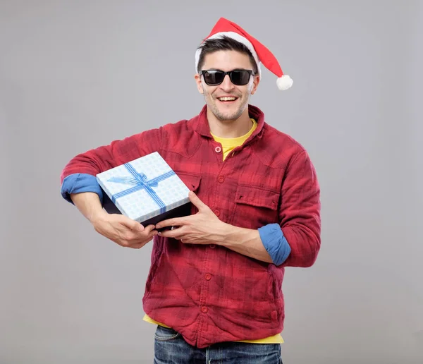 Молодой крутой человек в шляпе Санта-Клауса и подарок — стоковое фото