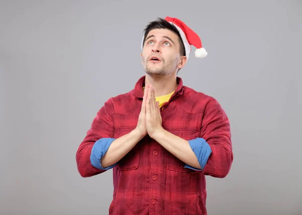 Nuori mies Santa Hat rukoilee — kuvapankkivalokuva
