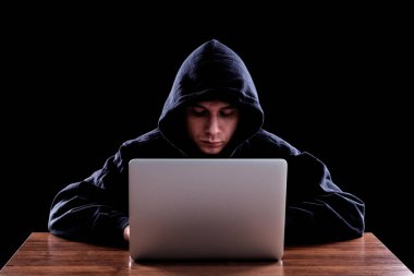 Karanlık bir defter önünde oturan hoody hacker