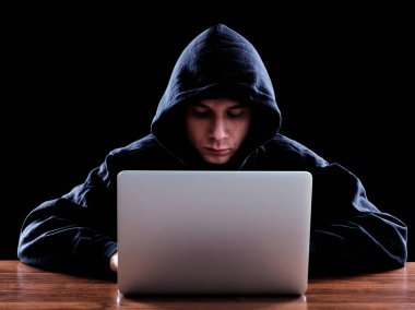 Karanlık bir defter önünde oturan hoody hacker