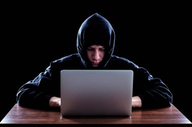 Karanlık bir defter önünde oturan hoody hacker