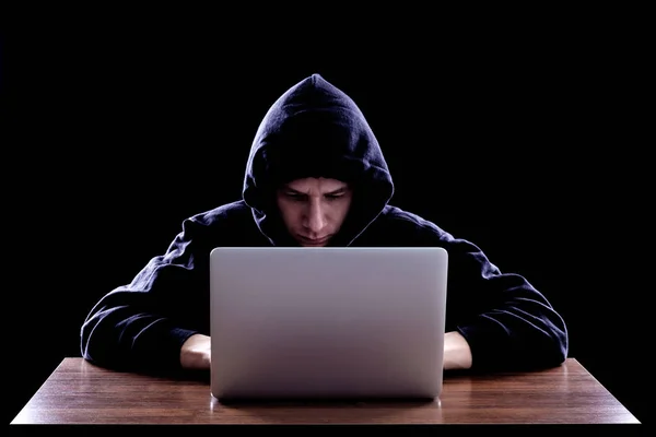 Hacker dalam hoody gelap duduk di depan notebook — Stok Foto