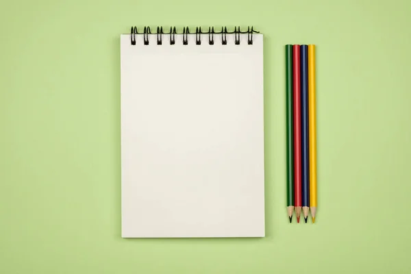Vista superior de la página del cuaderno en blanco con lápices de colores — Foto de Stock