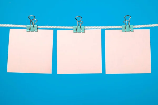 Hojas de papel rosa en blanco colgando de una cuerda — Foto de Stock