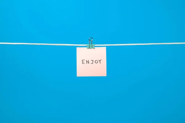 Uwaga różowy papier na clothesline z tekst Enjoy — Zdjęcie stockowe