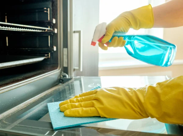 Man's hand in glove with rag cleaning oven — Stock Photo, Image