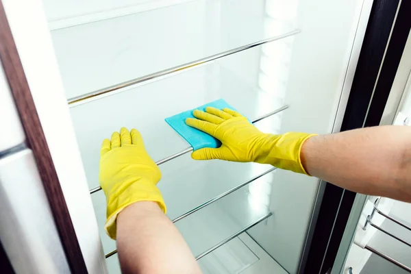 Man's hand cleaning white fridge with blue rag — Stock Photo, Image