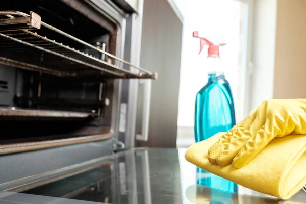 Man with bottle of spray and rag cleaning oven — Stock Photo, Image