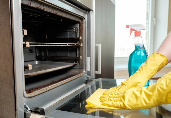 Man's hand in glove with rag cleaning oven — Stock Photo, Image