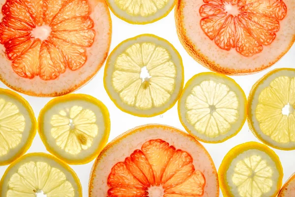 Helle süße Grapefruit- und Zitronenscheiben auf weißem Grund — Stockfoto