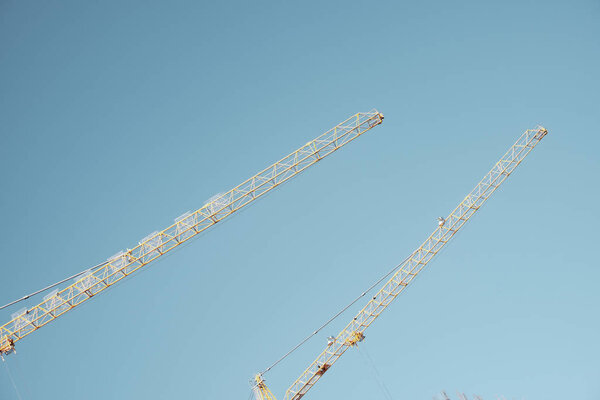Yellow cranes during construction of a new building over blue sky