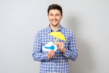 Holding model bir bulut mavi tuş ve sarı umbrel ile genç adam