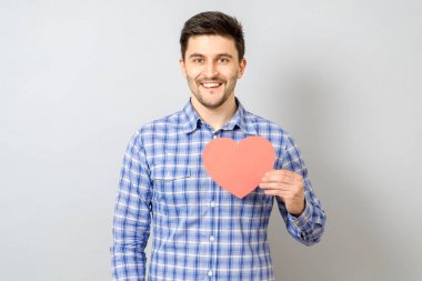 Kırmızı kağıt kalp tutan gülümseyen adam portresi