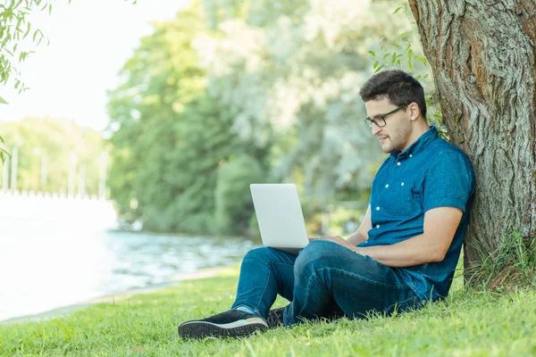 Adam açık havada doğa içinde oturan dizüstü bilgisayar ile