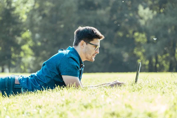 Homem usando laptop no parque da cidade — Fotografia de Stock