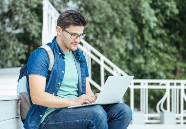 Ofis dışında dizüstü bilgisayar ile oturan adam