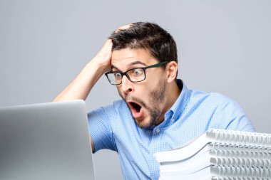 Genç dizüstü kullanarak mavi tişörtlü adam şok