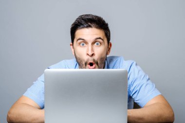 Genç dizüstü kullanarak mavi tişörtlü adam şok