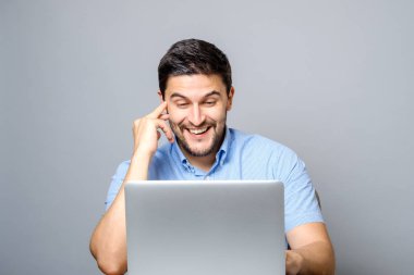 Laptop ile masaya oturan genç gülümseyen adam portresi