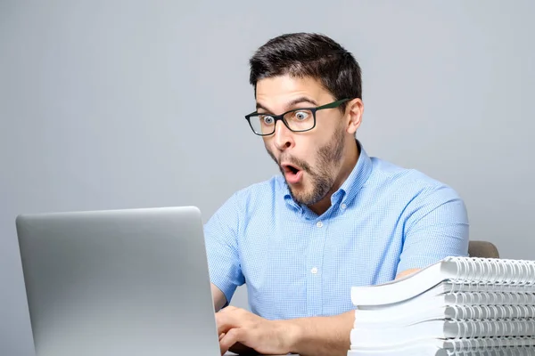 Jovem homem chocado em camisa azul usando laptop — Fotografia de Stock