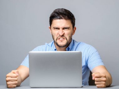 Laptop ile masada oturan kızgın adam