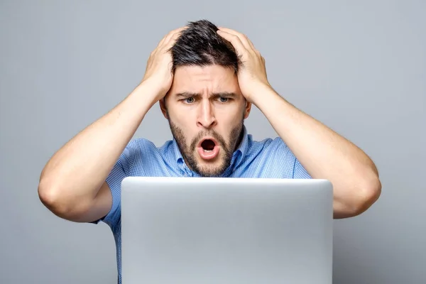 Junger schockierter Mann in blauem Hemd benutzt Laptop — Stockfoto