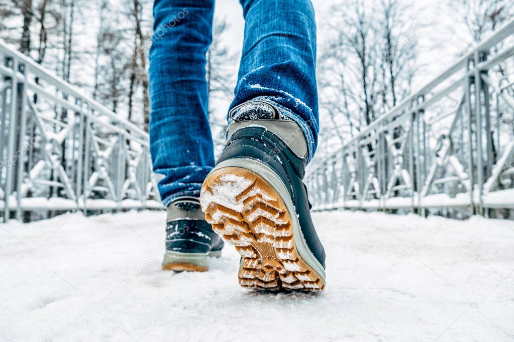 Man's legs in boots walking in the snow