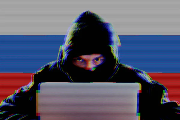 Karanlık bir dizüstü bilgisayar kullanarak Rus bayrağı ile hoody hacker