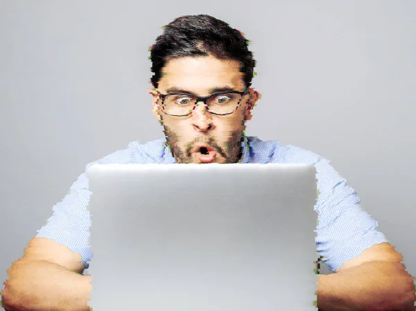 Junger schockierter Mann in blauem Hemd benutzt Laptop — Stockfoto