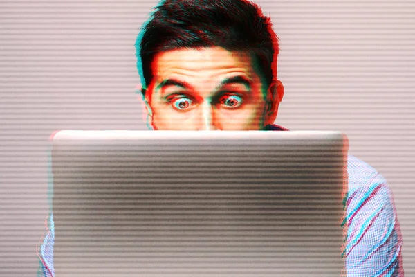 Young man in blauw shirt met behulp van laptop geschokt — Stockfoto
