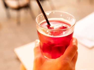 Bir kadının eli gün batımına karşı bir bardak sangria tutuyor.