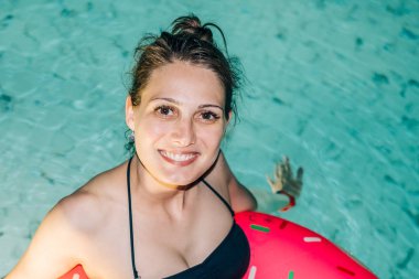 Geceleri otel havuzunda şişme yüzüklü güzel bir kadın.