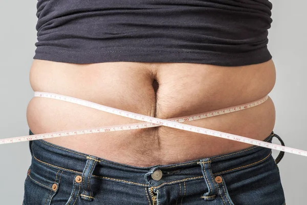 Man check out his body fat with measuring tape