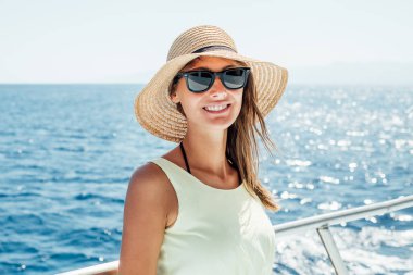 Yaz tatili boyunca teknede gülümseyen genç bir kadın.