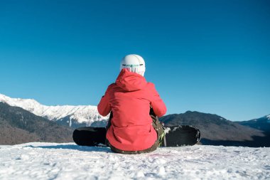 Spor giyimli snowboardcuların arka görüntüsü ve ekipmanlar dinleniyor.