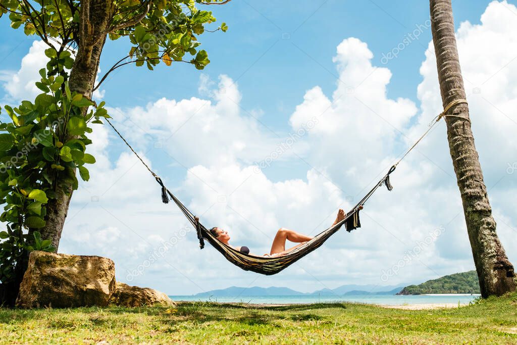 Happy woman in black bikini relaxing in hammock