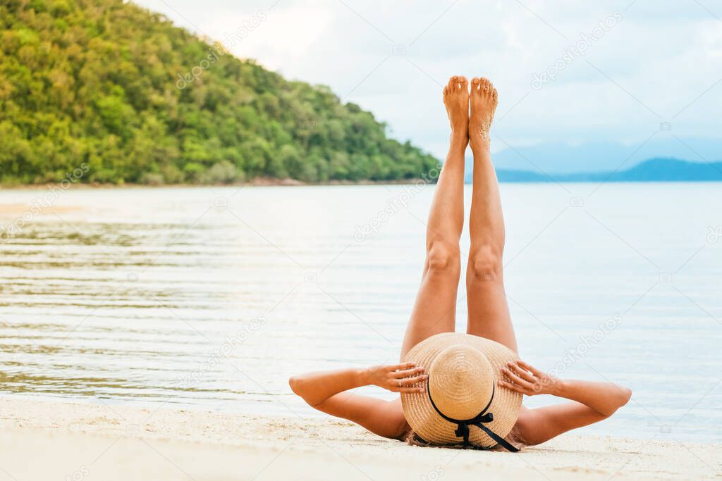 Beautiful woman lying on a tropical beach with legs raised up hi