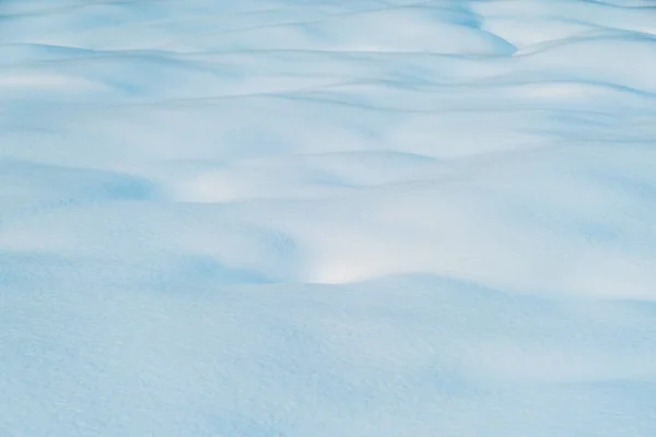 Witte en blauwe besneeuwde textuur van natuurlijk sneeuwoppervlak — Stockfoto