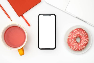 Beyaz ofis masası boş ekranlı akıllı telefon, dizüstü bilgisayar ve malzemeler. Üst görünüm, kopyalama alanı, düz uzanma