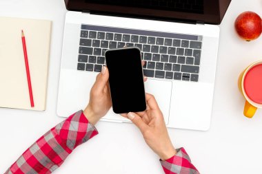 Kadın el ele tutuşmasını ve bilgisayarın arka planında boş ekranlı siyah cep telefonu kullanmasını görüntüle. Üst Manzara. Düz yatıyordu