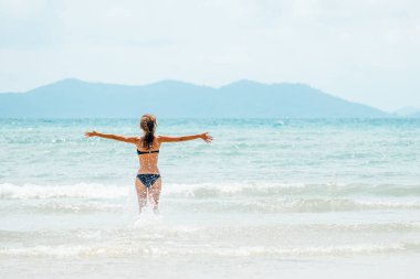 Mutlu kaygısız kadın bikini giyiyor yaz tatilinde eğleniyor. Tropikal tatilde okyanus suyunda kolları açık koşan komik kız.