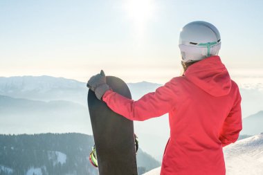 Snowboard yapan ve dağ manzarasının tadını çıkaran kadın snowboardcu. Snowboard konsepti