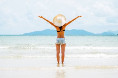 Güzel, esmer, elleri havada, okyanusa bakan genç bir kızın arka manzarası. Özgürlük kavramı