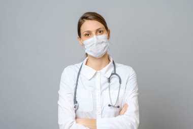 Krizi çözmek için ameliyat maskesi takan mutlu bir doktor. Gri arkaplanda izole