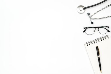 Renkli masa üzerinde not defteri ve steteskopu olan bir doktorun işyeri. Üst görünüm