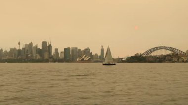 Sidney Limanı 'nın ortasındaki yelkenli yatı. CBD limanı. Çalı yangınları sırasında hava kirliliği ve gün batımında..