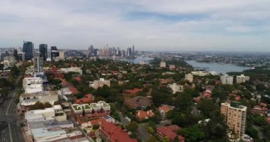 Sydney 'nin aşağı kuzey kıyısındaki yeşil yapraklı banliyöleri aydınlık bir günde şehrin CBD' sine doğru havadan görünüyor..