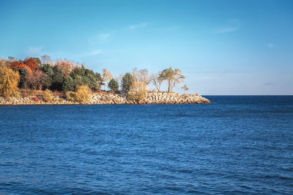 Hermoso paisaje al atardecer en el lago canadiense Ontario, cielo azul claro con nubes, árboles otoñales en una pequeña isla en el agua, espacio para texto — Foto de Stock